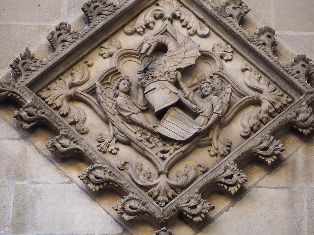 A stone shield with two angels, a helmet and a dragon on the Barcelona city hall, Ajuntament. Sant Jaume square, Gothic Quarter