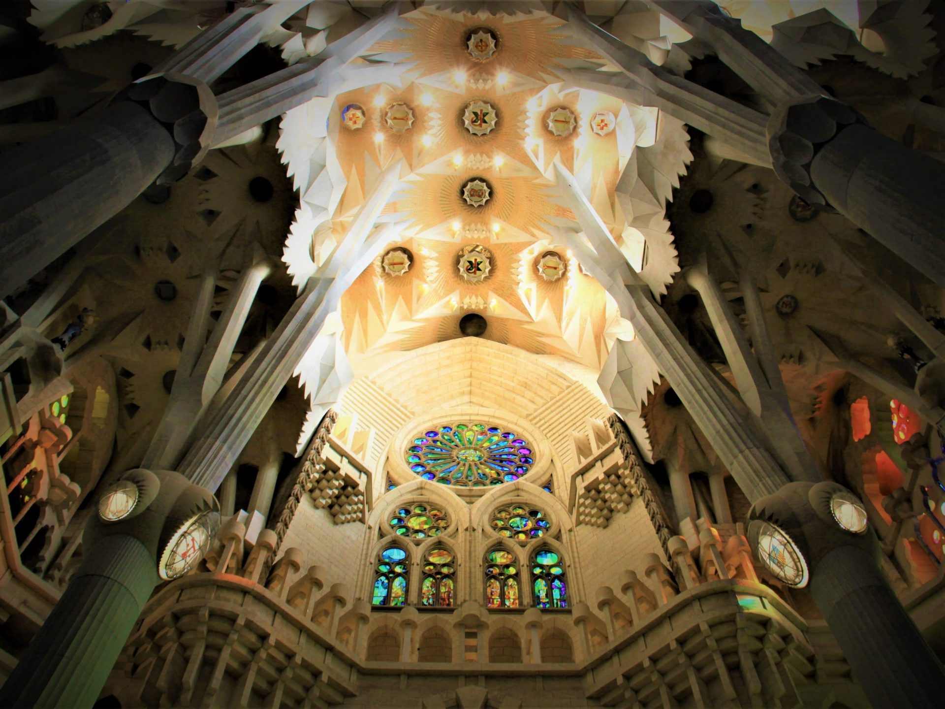 Sagrada Familia by Gaudi inside. Stone columns, geometrical ceiling and colored stained-glass.